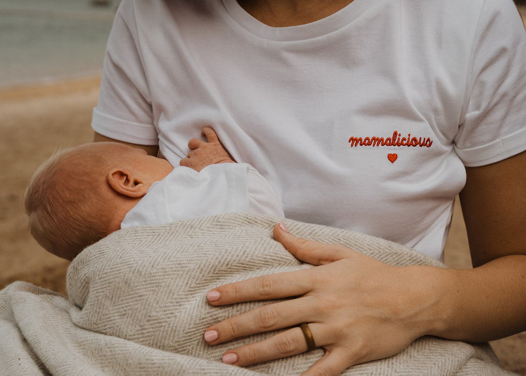 Our organic nursing top "Mamalicious" made of 100% premium organic cotton has lateral openings on both sides of the t-shirt closed by easy-to-open snap buttons. Our breastfeeding t-shirts are soft like a cocoon! The nursing top is white and has a red embroidery "Mamalicious" with a heart - on the left side - close to the heart.